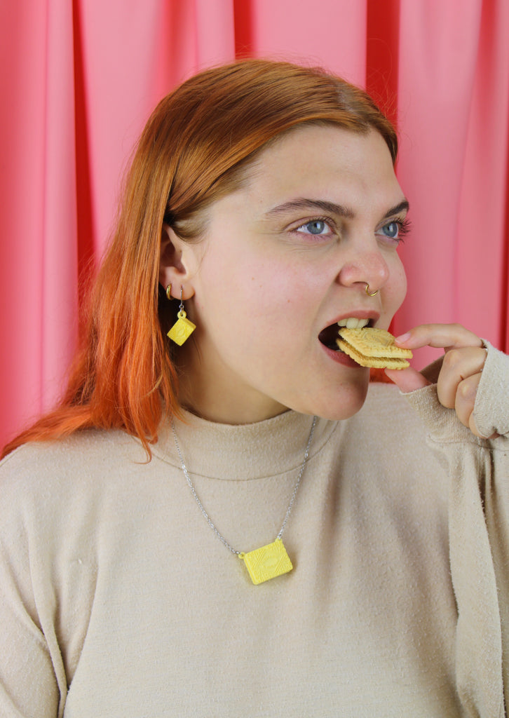 Woman eating a custard cream biscuit wearing custard cream jewellery