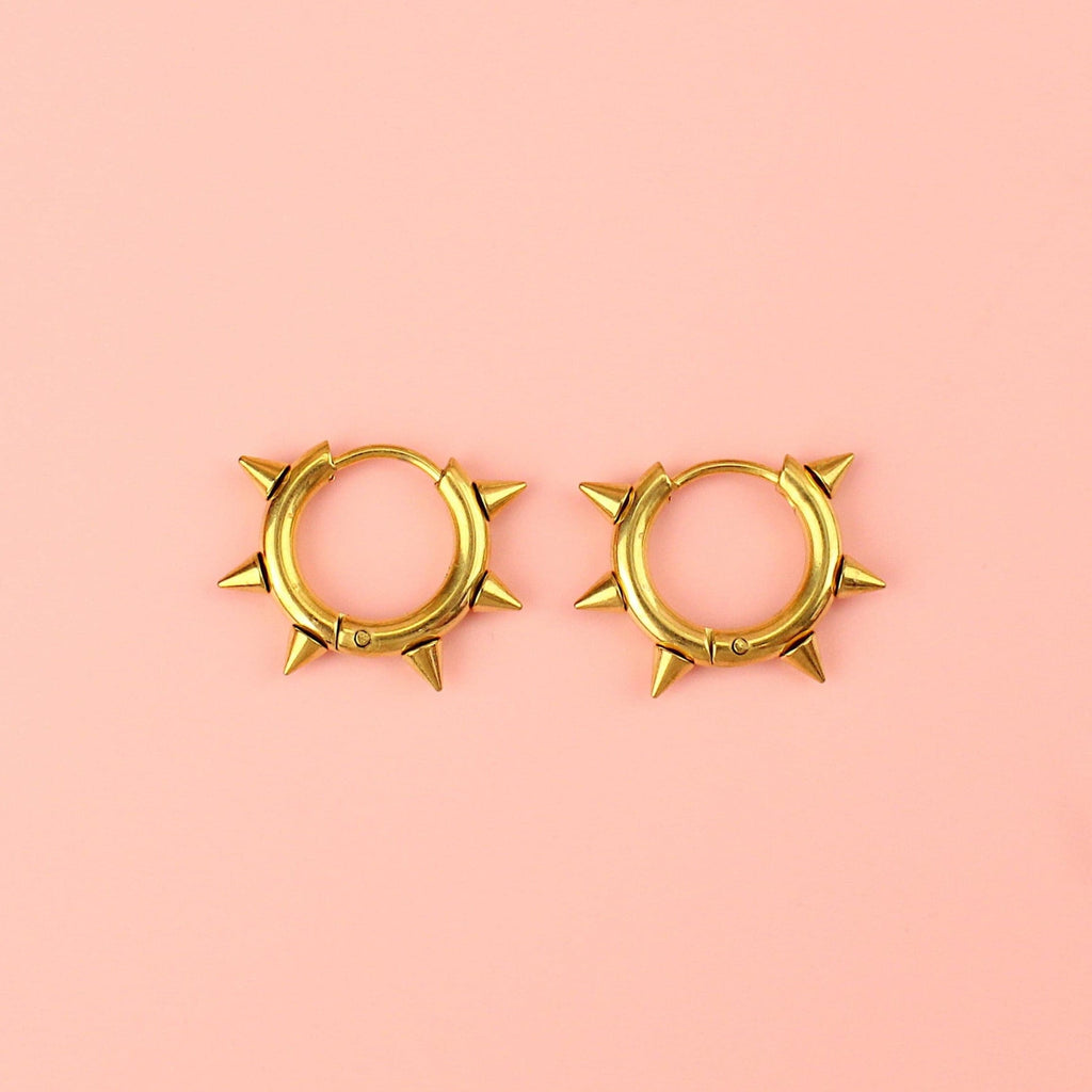 Gold plated stainless steel huggie hoops with punk-inspired spikes surrounding the edge 