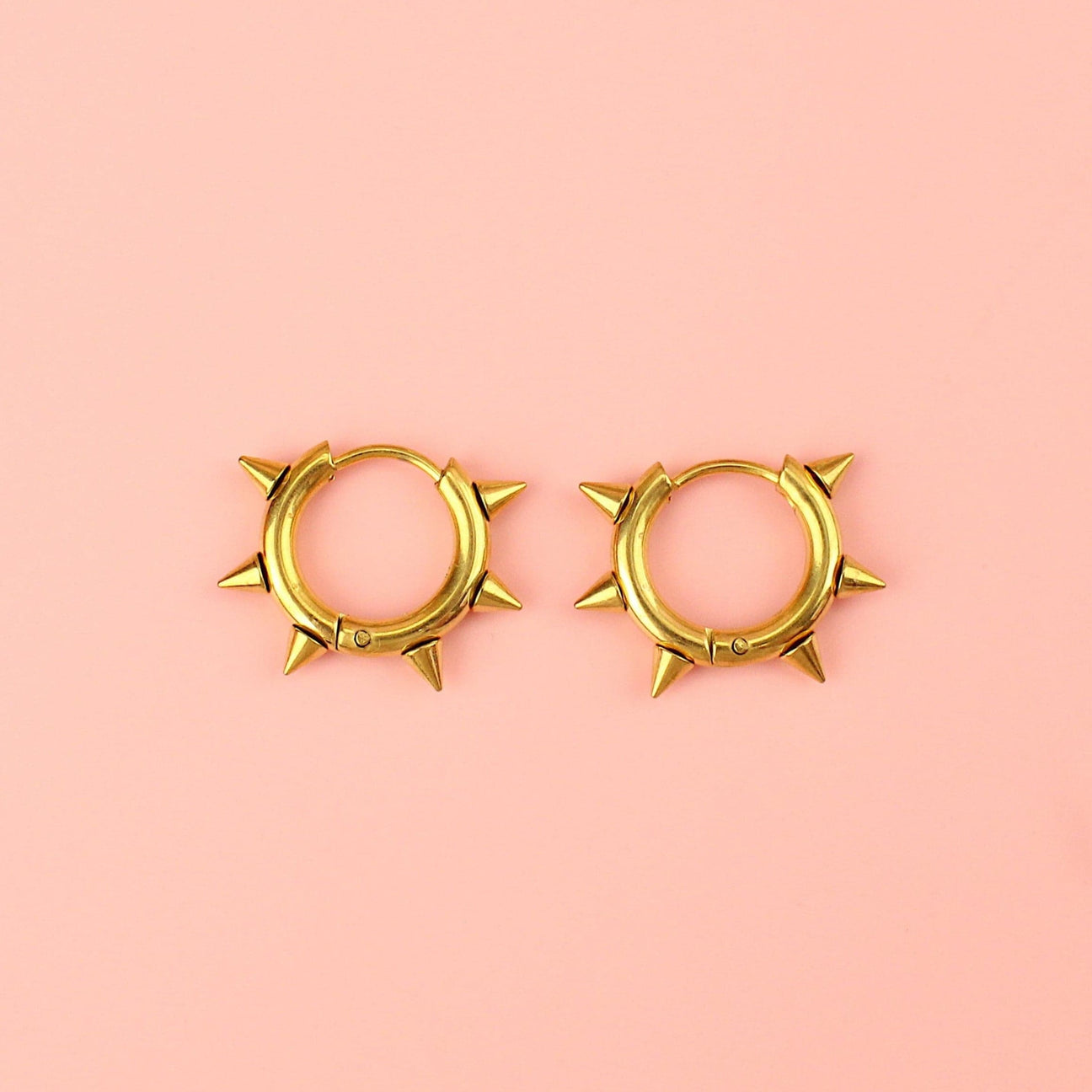 Gold plated stainless steel huggie hoops with punk-inspired spikes surrounding the edge 