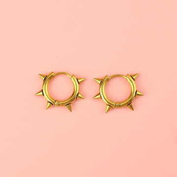 Gold plated stainless steel huggie hoops with punk-inspired spikes surrounding the edge 