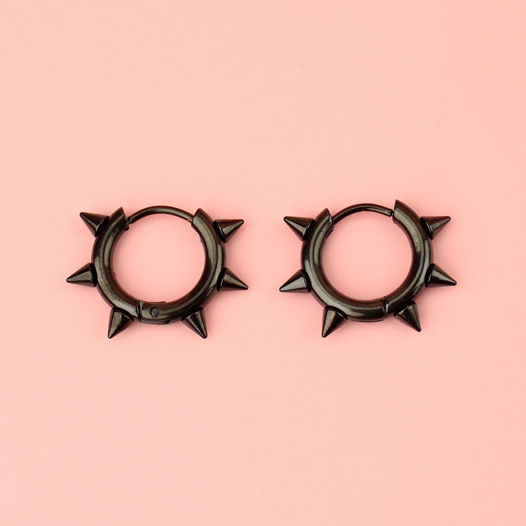 Black stainless steel huggie hoops with punk-inspired spikes surrounding the edge 