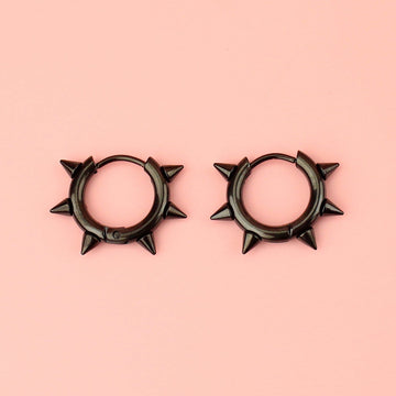 Black stainless steel huggie hoops with punk-inspired spikes surrounding the edge 
