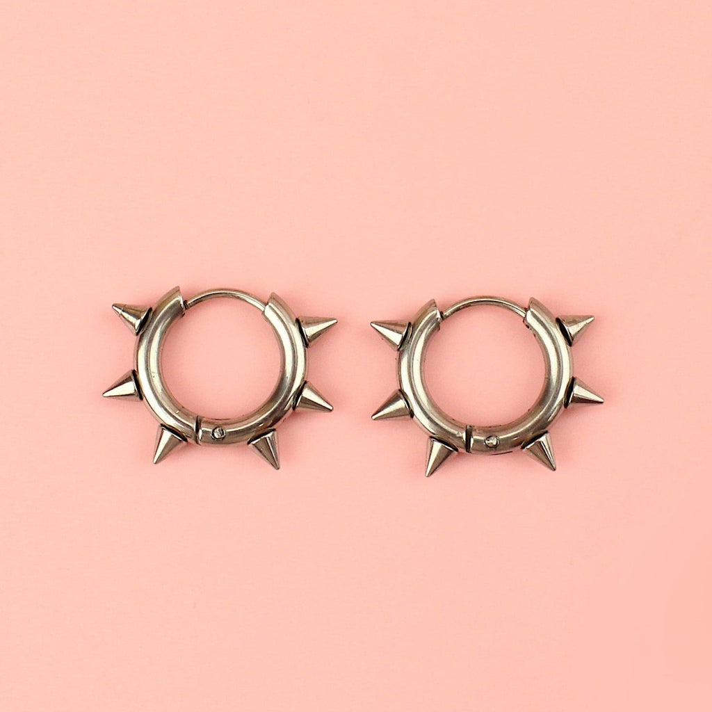 Stainless steel huggie hoops with punk-inspired spikes surrounding the edge 