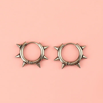 Stainless steel huggie hoops with punk-inspired spikes surrounding the edge 