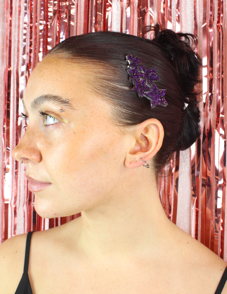 Model wearing a hair clip made up of a cluster of purple glittery stars