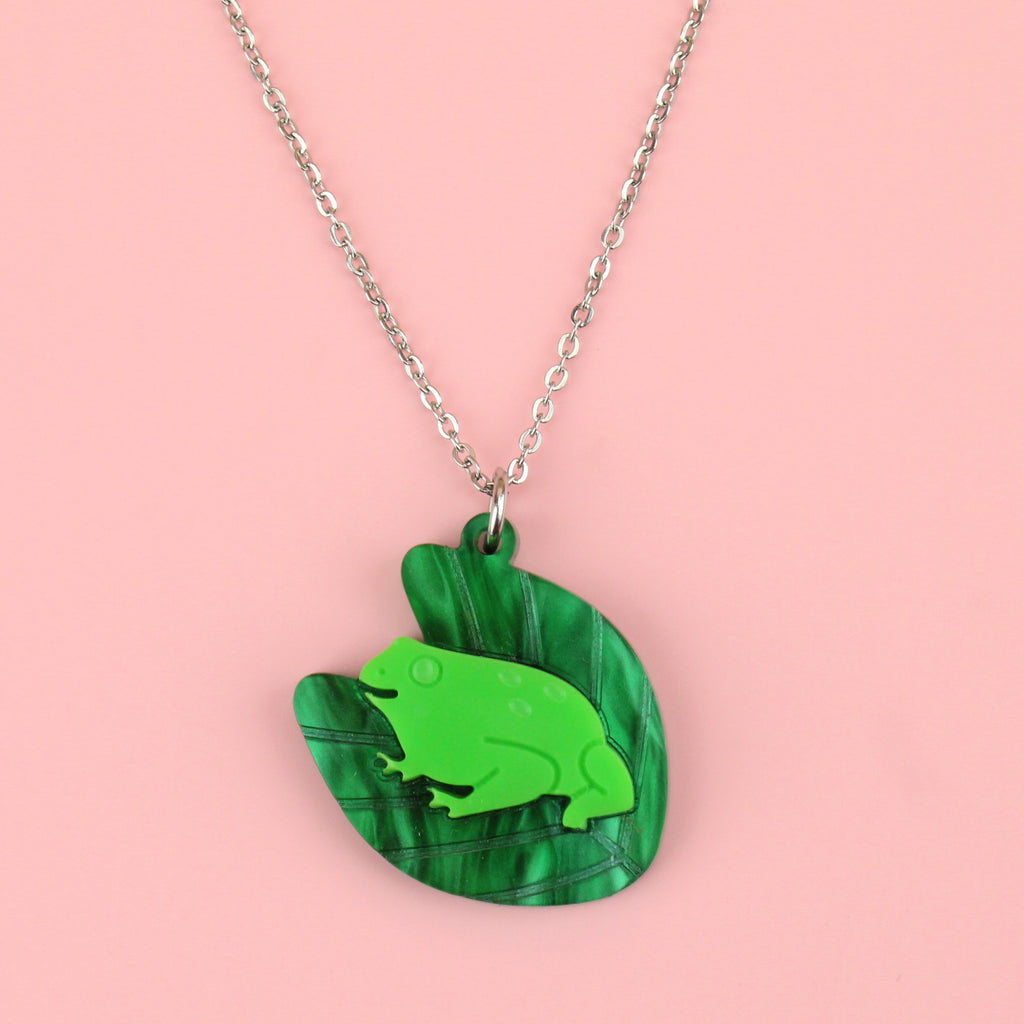A dark green marble lily pad pendant with a bright green frog in the middle on a stainless steel chain
