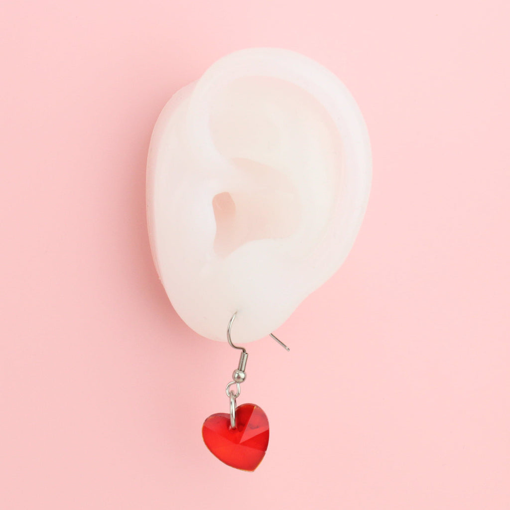 Ear wearing red heart shaped glass charms on stainless steel earwires