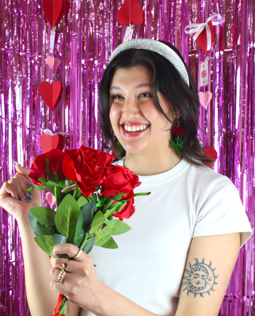 model wearing red mirror acrylic roses and charming green acrylic thorn charms joined together hanging from stainless steel earwires