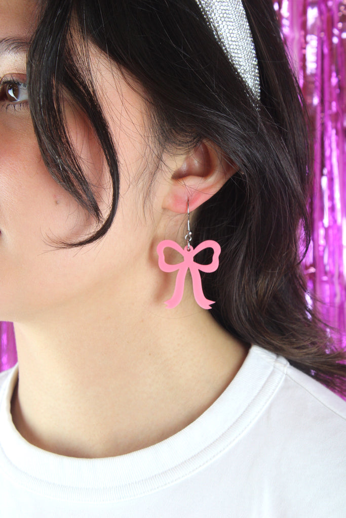 Model wearing Rose pink bow shaped charms on stainless steel earwires