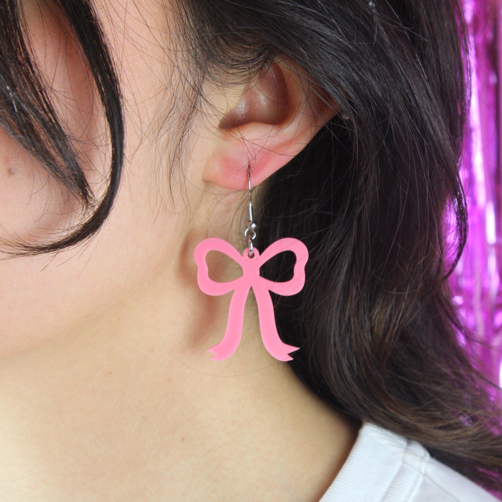 Model wearing Rose pink bow shaped charms on stainless steel earwires