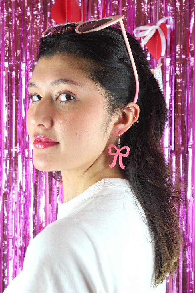 Model wearing Rose pink bow shaped charms on stainless steel earwires