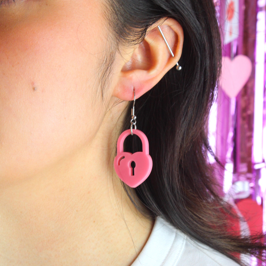 Model wearing Rose pink heart padlock charm on a stainless steel earwire