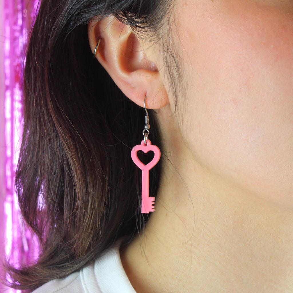 Model wearing Rose pink key charm on a stainless steel earwire
