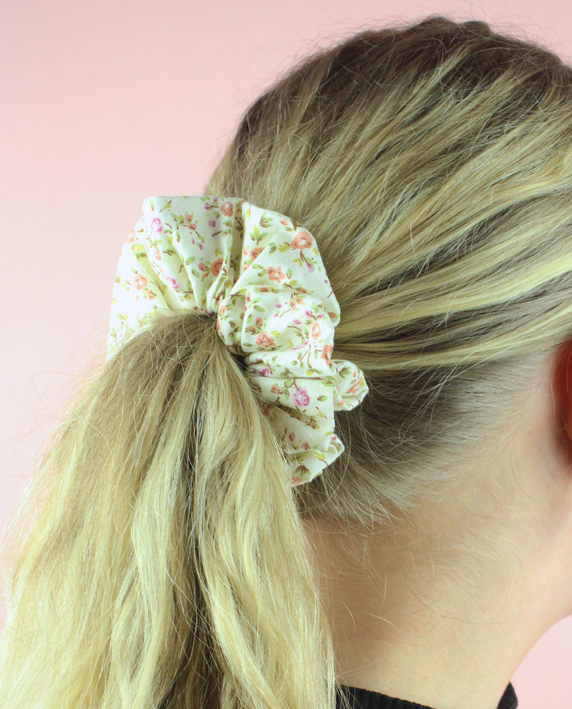 Model wearing cream coloured scrunchie featuring peach and pink coloured roses