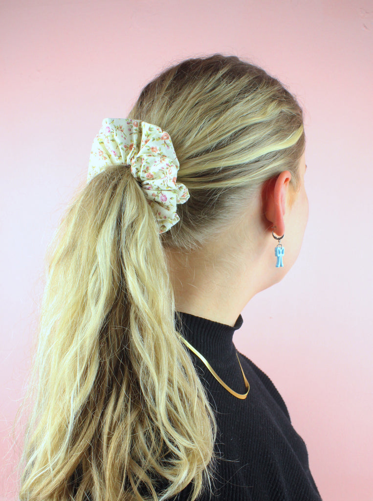 Model wearing cream coloured scrunchie featuring peach and pink coloured roses