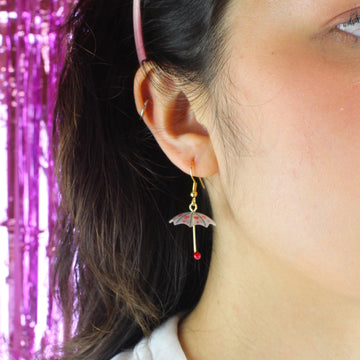 Model wearing 3D umbrella charms with a red heart detail and red handles on gold plated stainless steel earwires