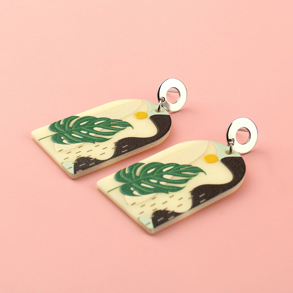Stainless steel studs with acrylic charms featuring a monstera print and abstract view