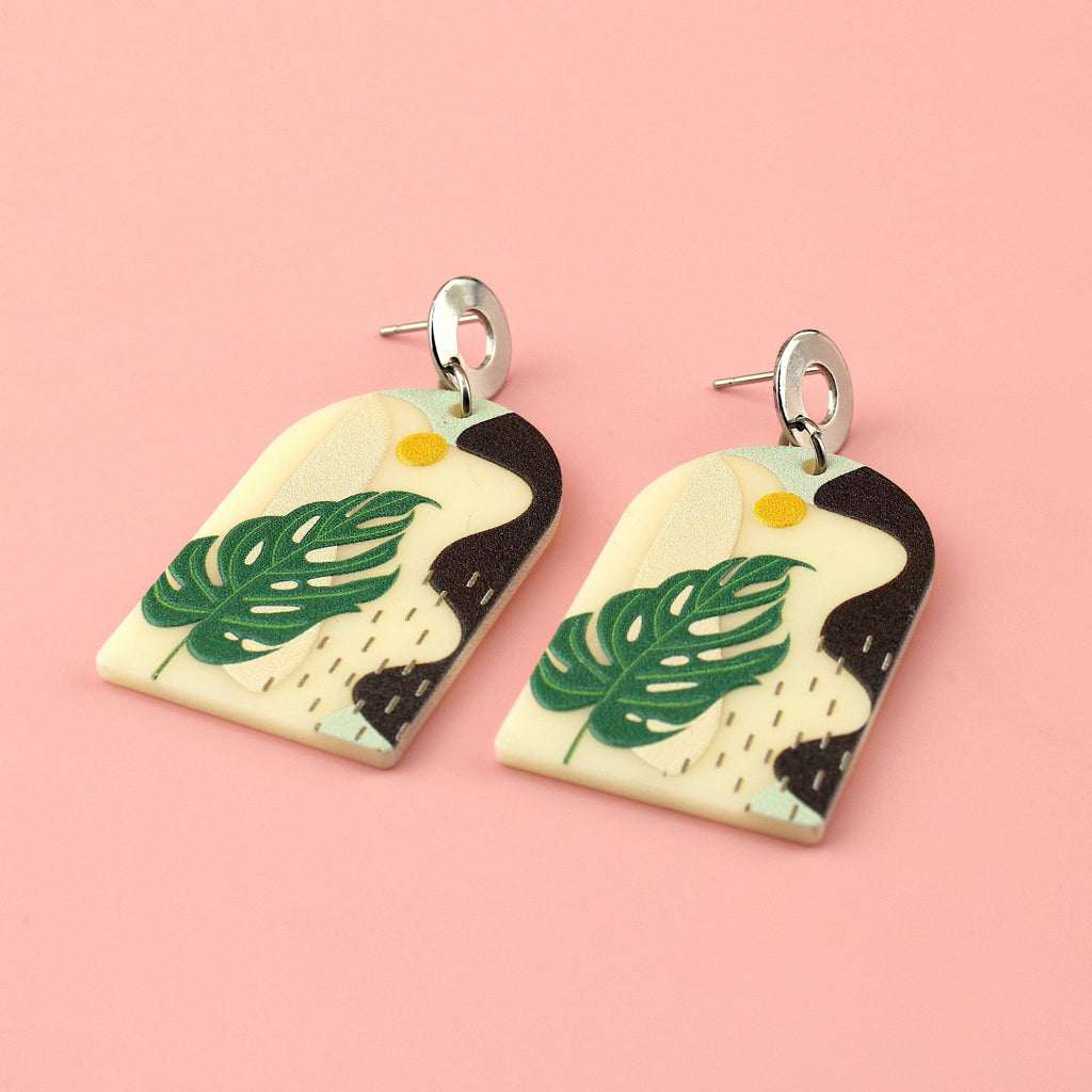 Stainless steel studs with acrylic charms featuring a monstera print and abstract view