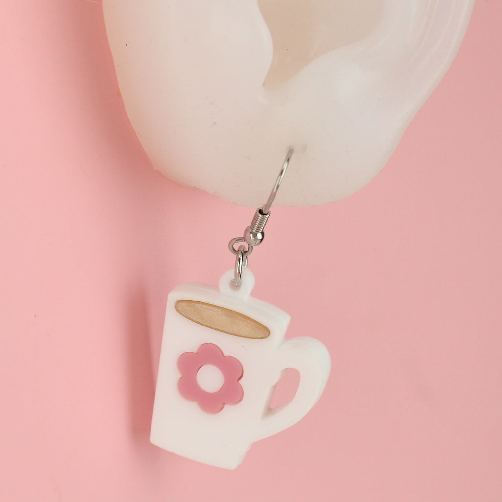 ear shwoing cup of tea charm with a pink flower design on a stainless steel earwires