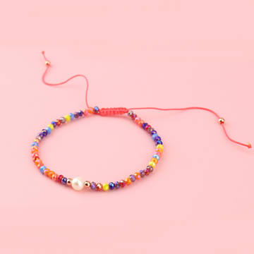 Multicoloured glass beads and a faux pearl on an adjustable nylon thread bracelet