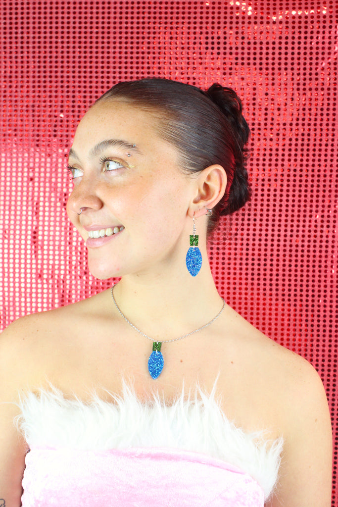 Blue Christmas Light Bulb Pendant with a green top on a stainless steel chain, model is also wearing matching earrings