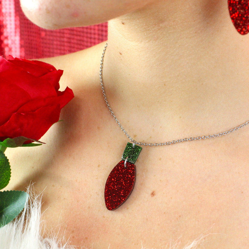 Red Christmas Light Bulb Pendant with a green top on a stainless steel chain,  model is also wearing matching earrings