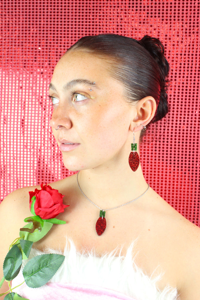 Red Christmas Light Bulb Pendant with a green top on a stainless steel chain, model is also wearing matching earrings