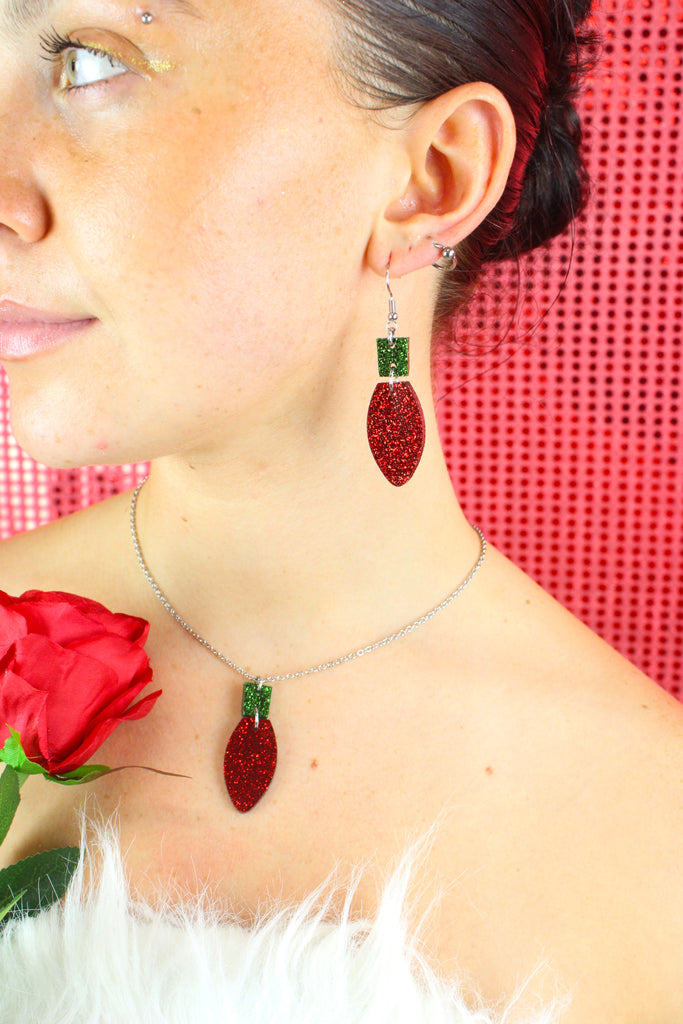 Model wearing red christmas light bulb charms with a green top on stainless steel earwires, shown with matching necklace