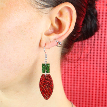 Model wearing red christmas light bulb charms with a green top on stainless steel earwires