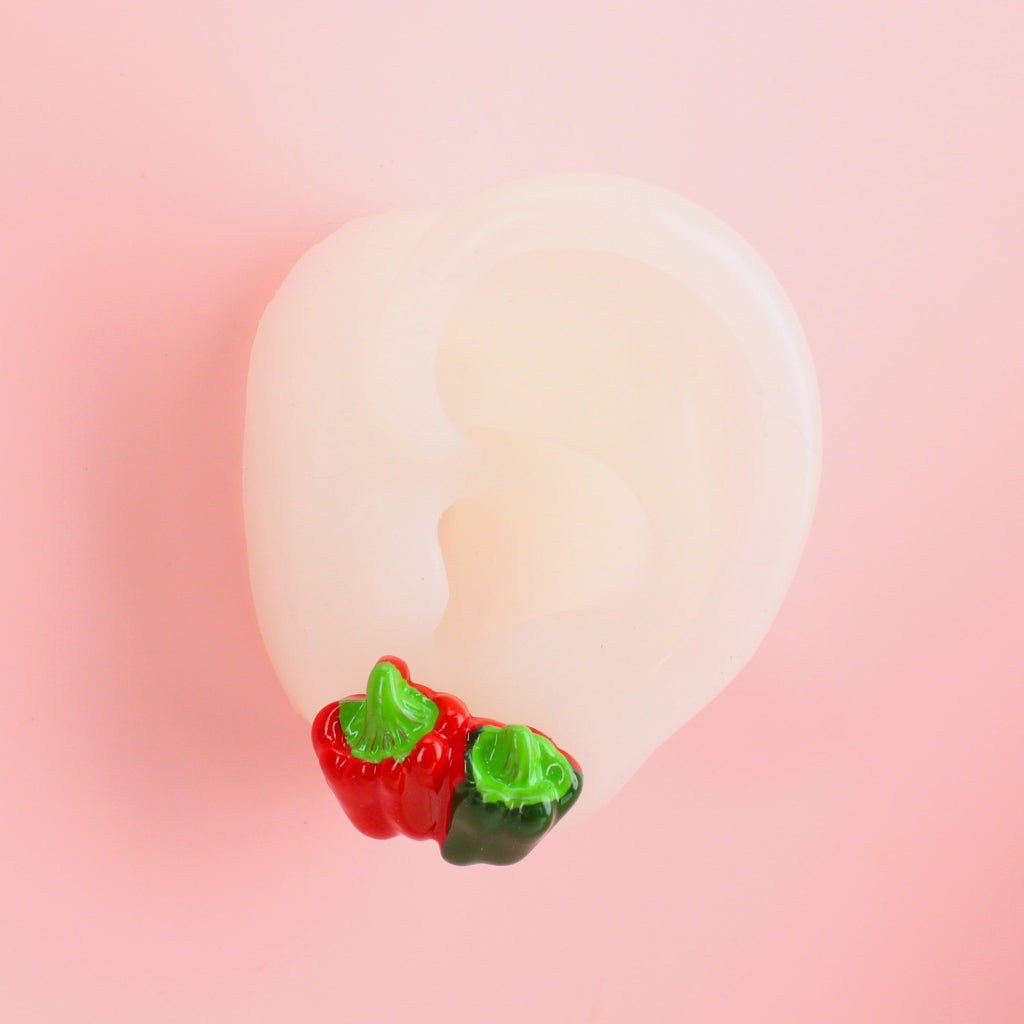 ear wearing red and green pepper studs joined together with red glittery back