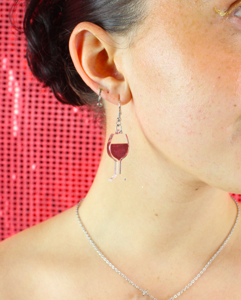 Model wearing earring that features a glass of red wine