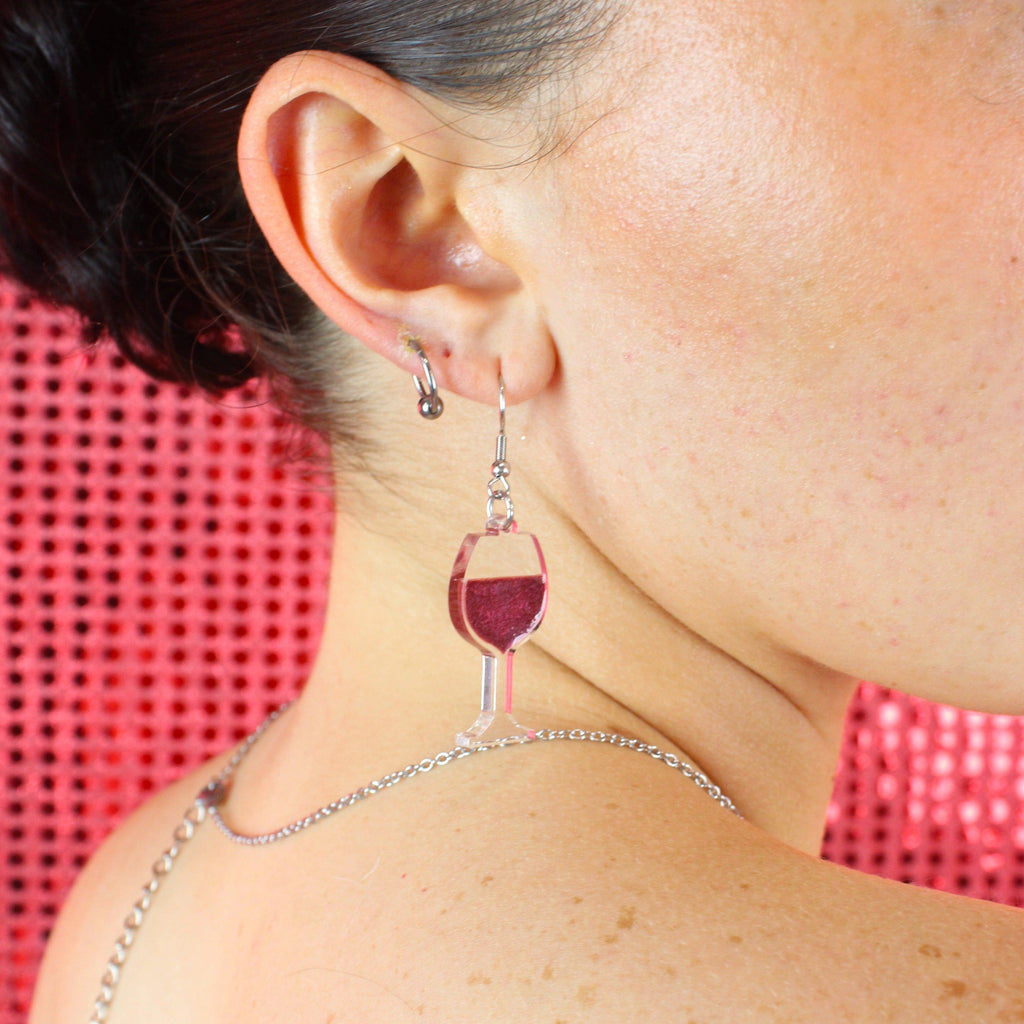 Model wearing earring that features a glass of red wine