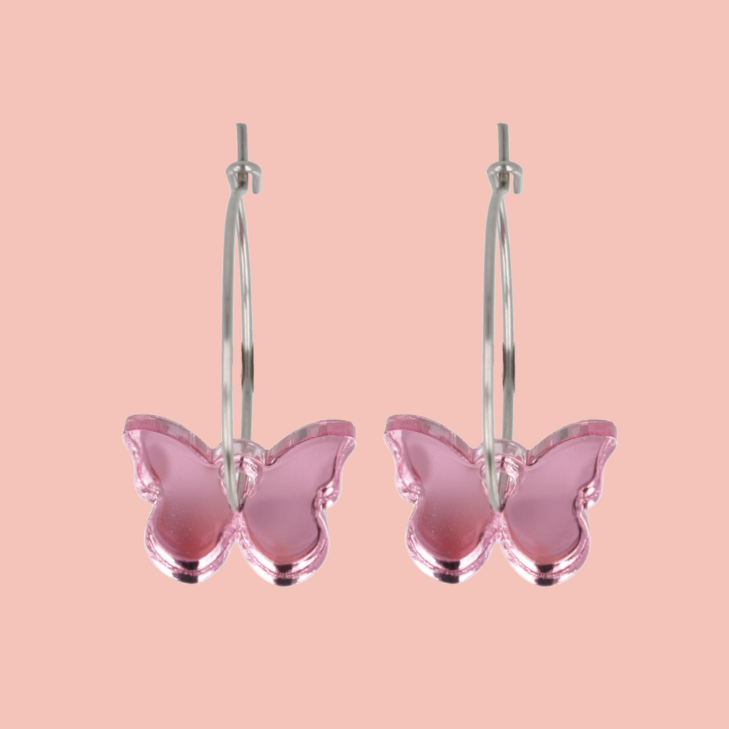 Pink butterfly earrings on a pink background