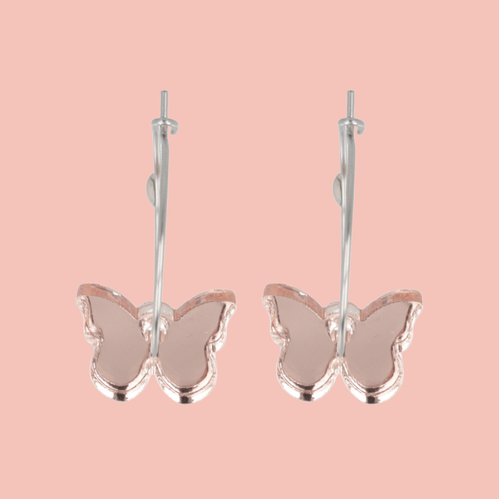Butterfly-shaped earrings on a pink background