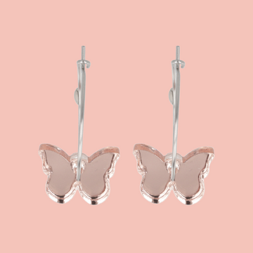 Butterfly-shaped earrings on a pink background