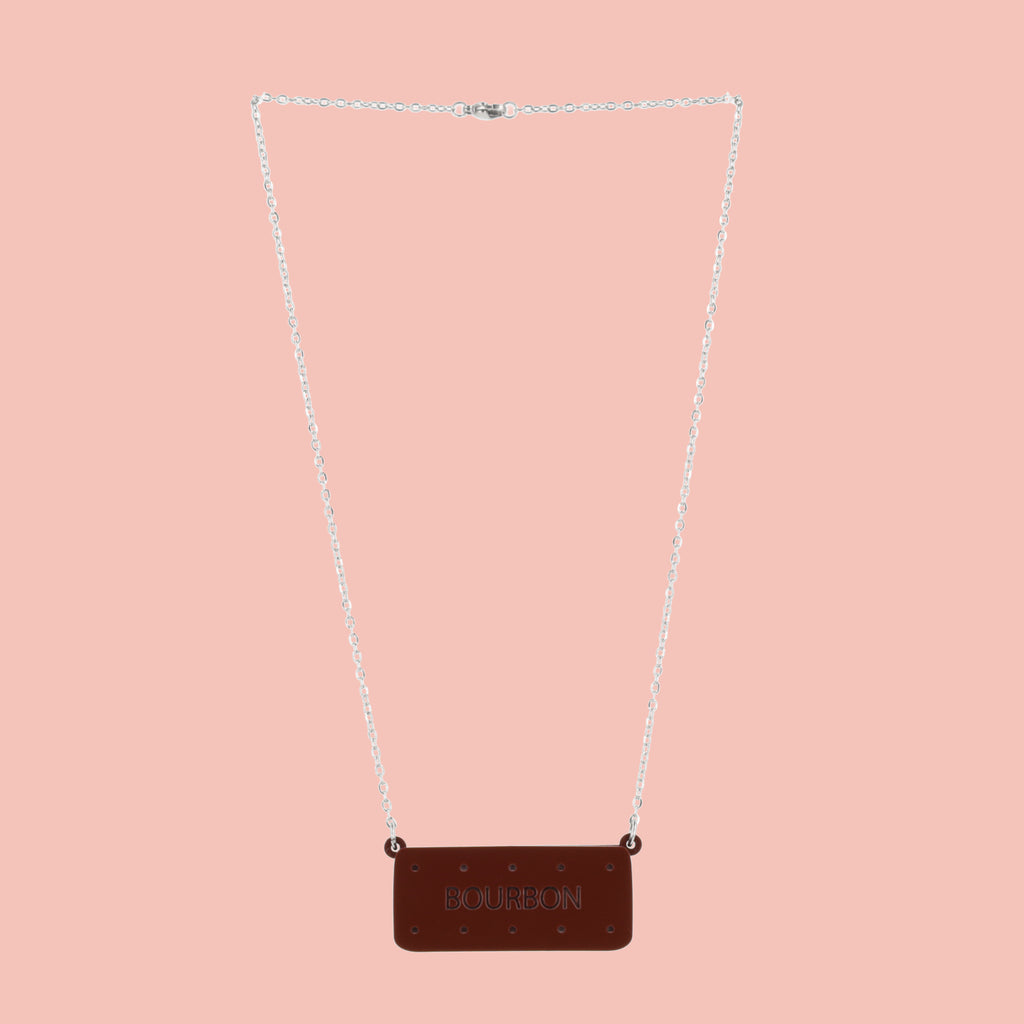 Necklace with a bourbon biscuit pendant on a pink background