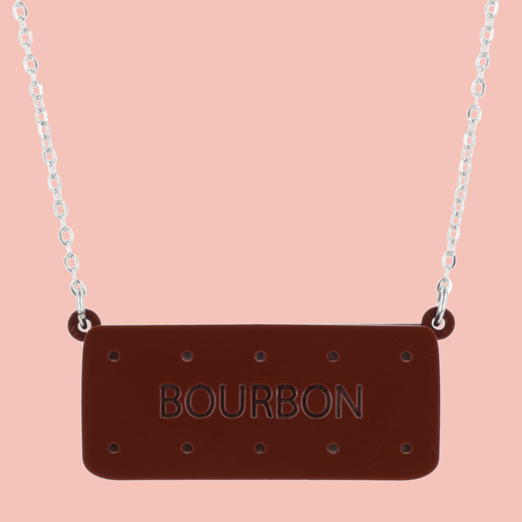 Necklace with a bourbon biscuit pendant on a pink background