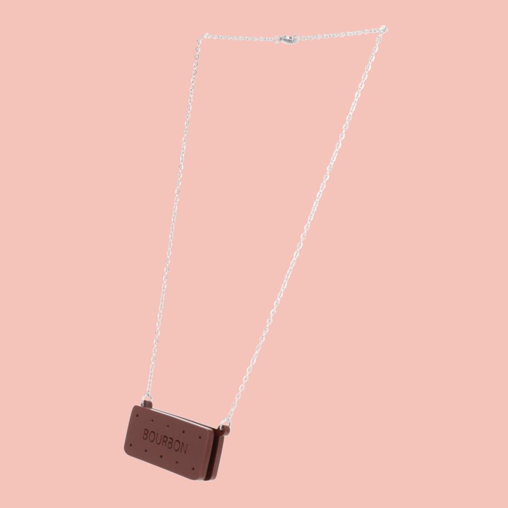 Necklace with a bourbon biscuit pendant on a pink background