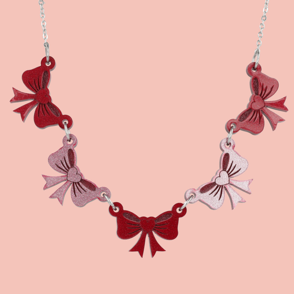 Necklace with red and pink bow-shaped pendants on a pink background