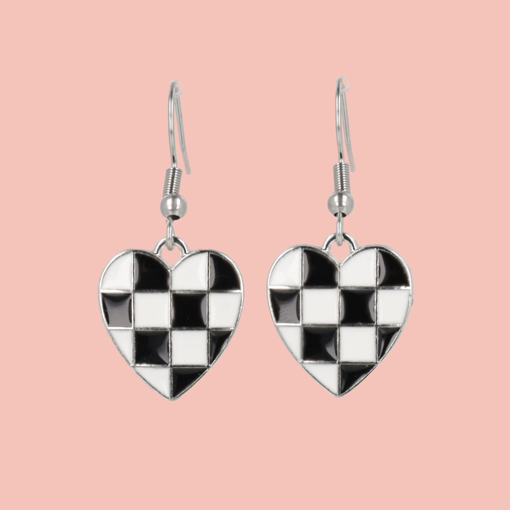 Checkered heart-shaped earrings on a pink background