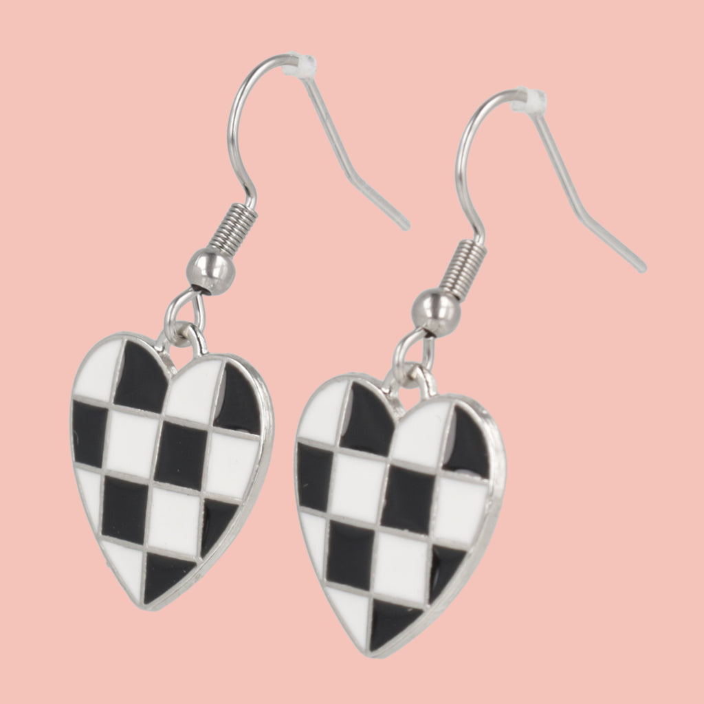 Checkered heart-shaped earrings on a pink background