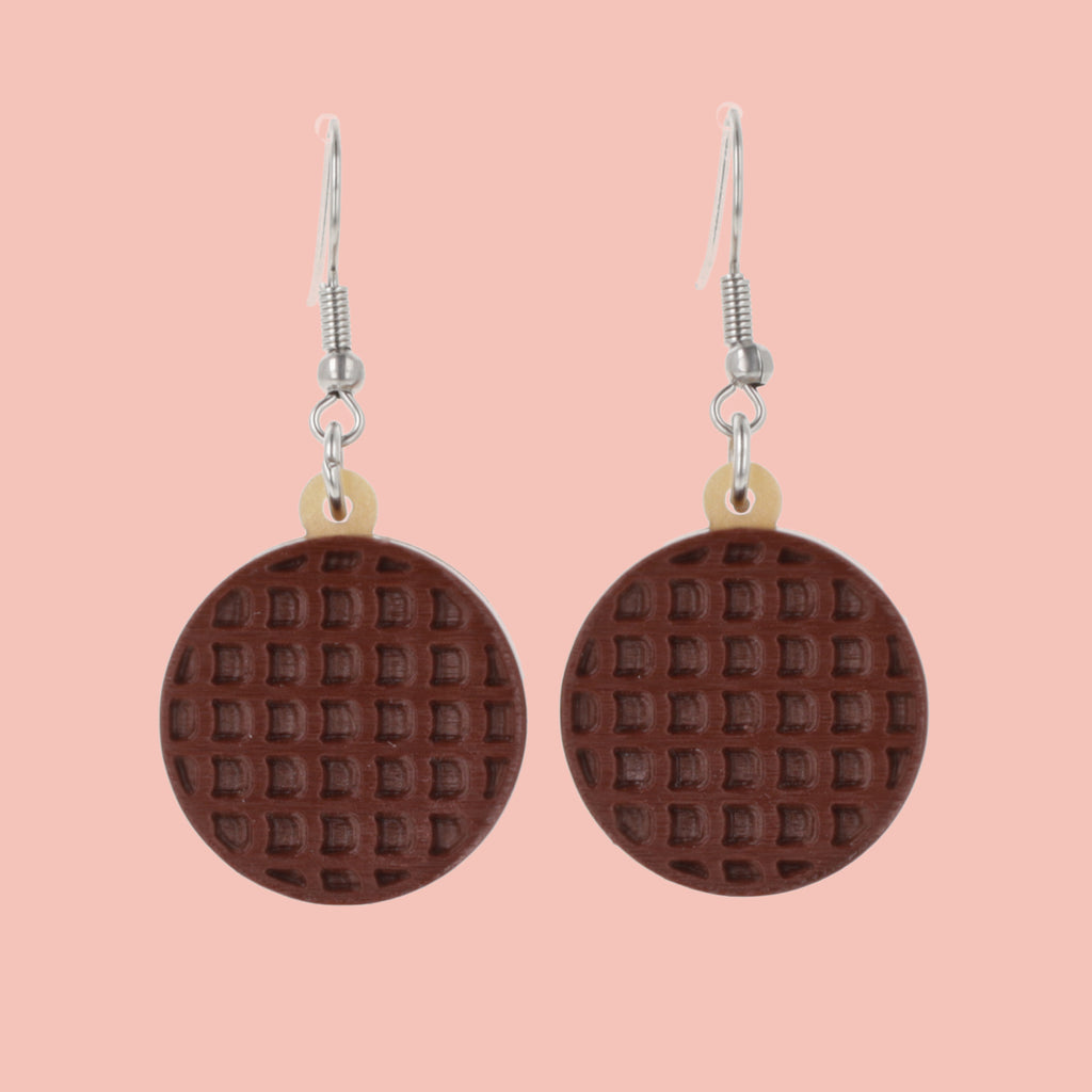 Chocolate digestive earrings on a pink background