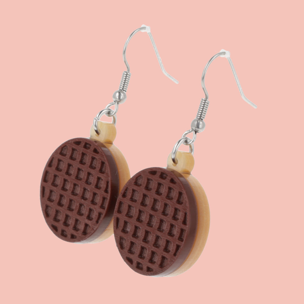Chocolate digestive earrings on a pink background