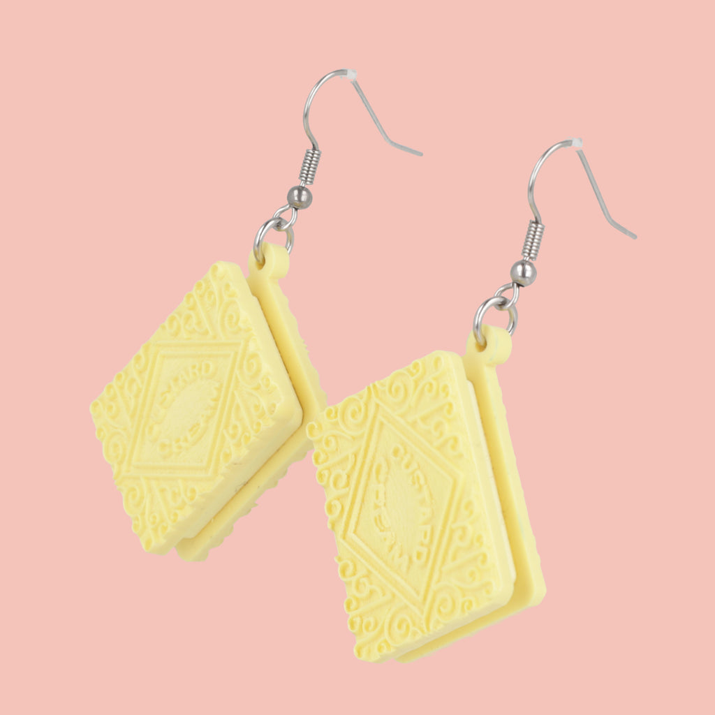 Custard cream earrings on a pink background