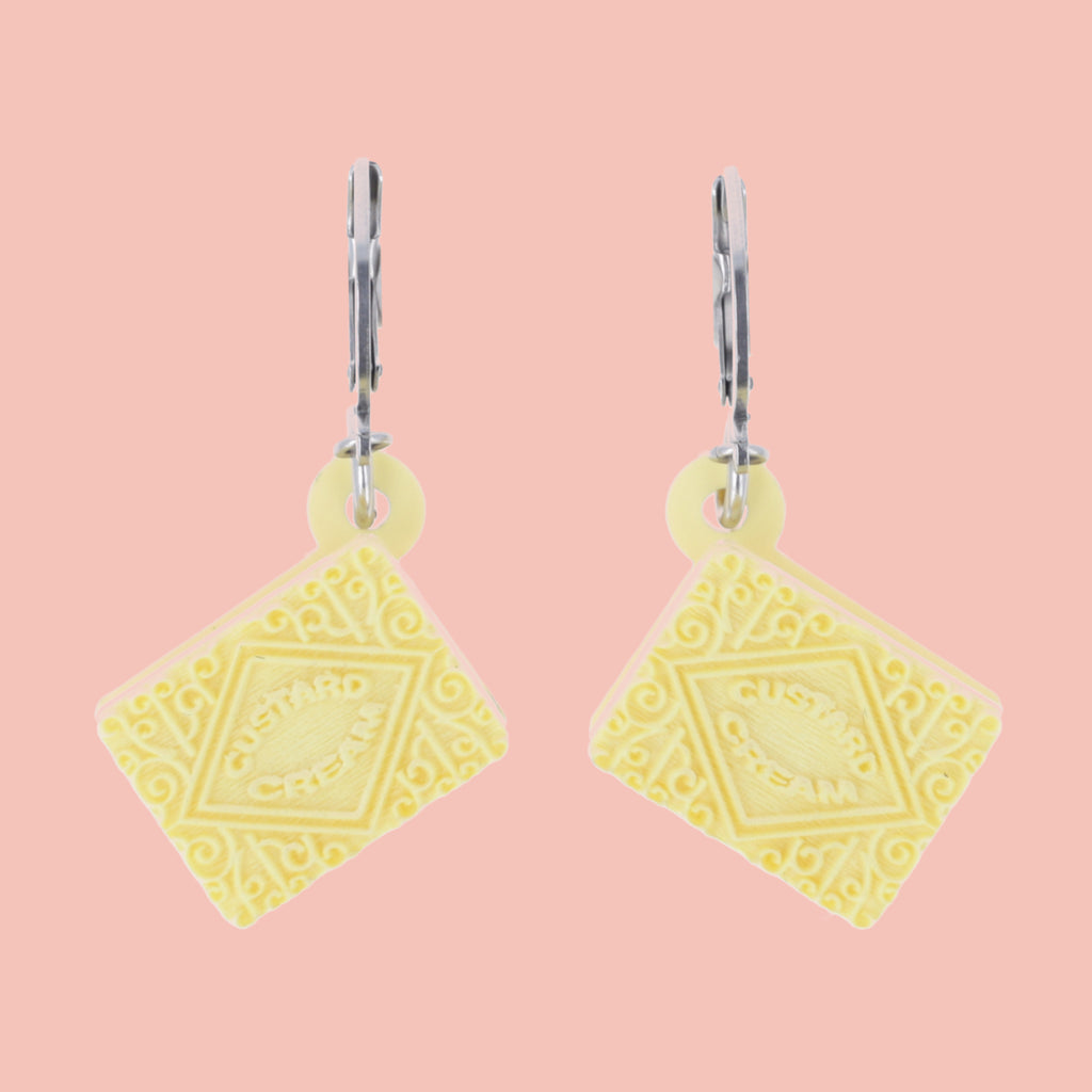 custard cream huggie hoops on a pink background