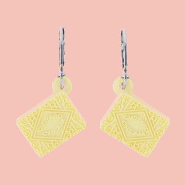 custard cream huggie hoops on a pink background