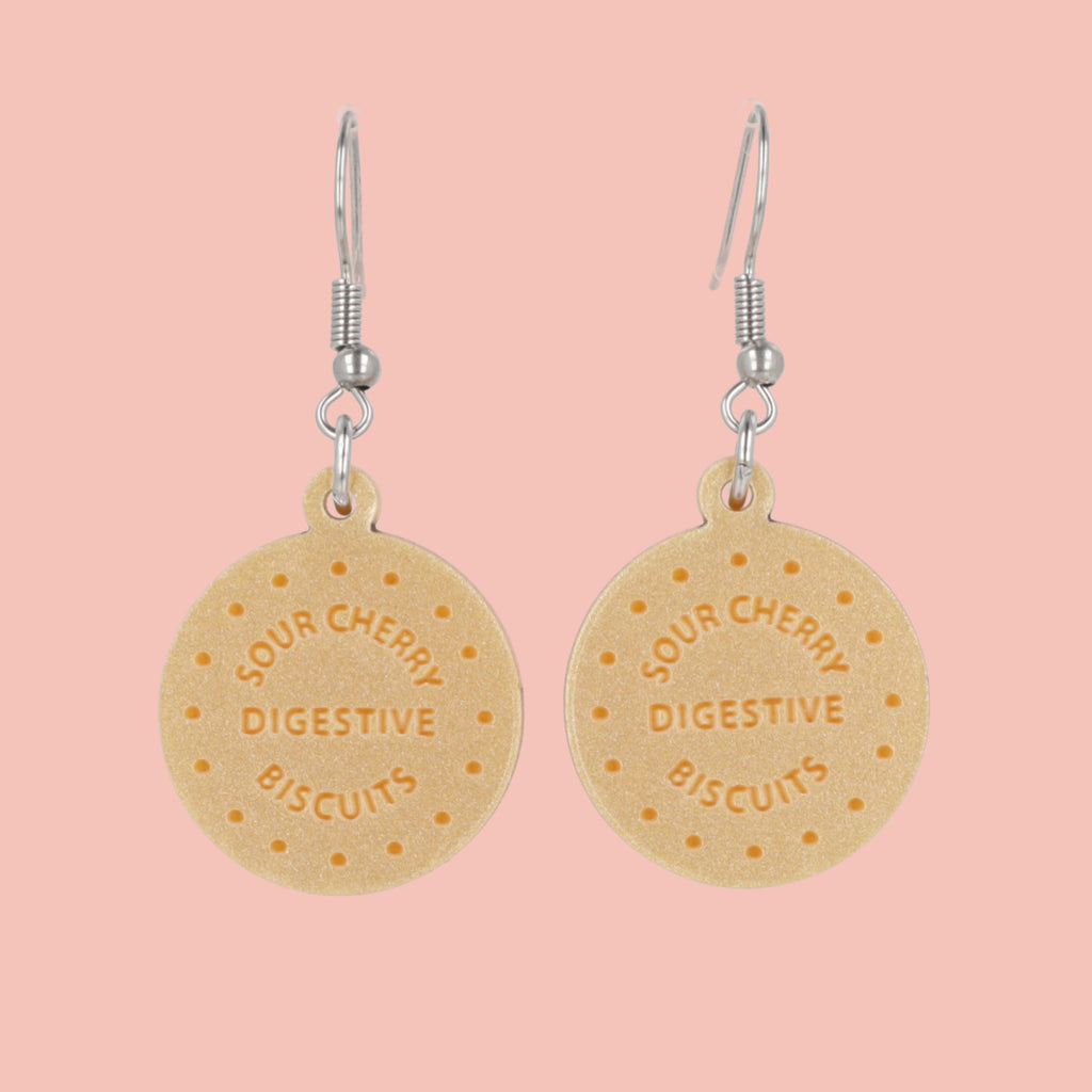 Digestive biscuit earrings on a pink background