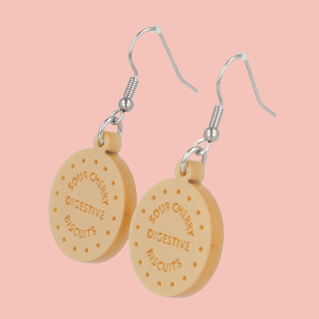 Digestive biscuit earrings on a pink background