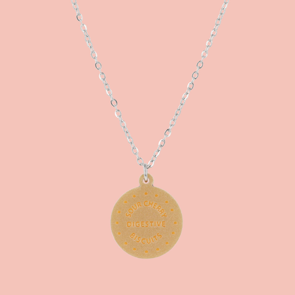 Necklace with a digestive biscuit pendant on a pink background