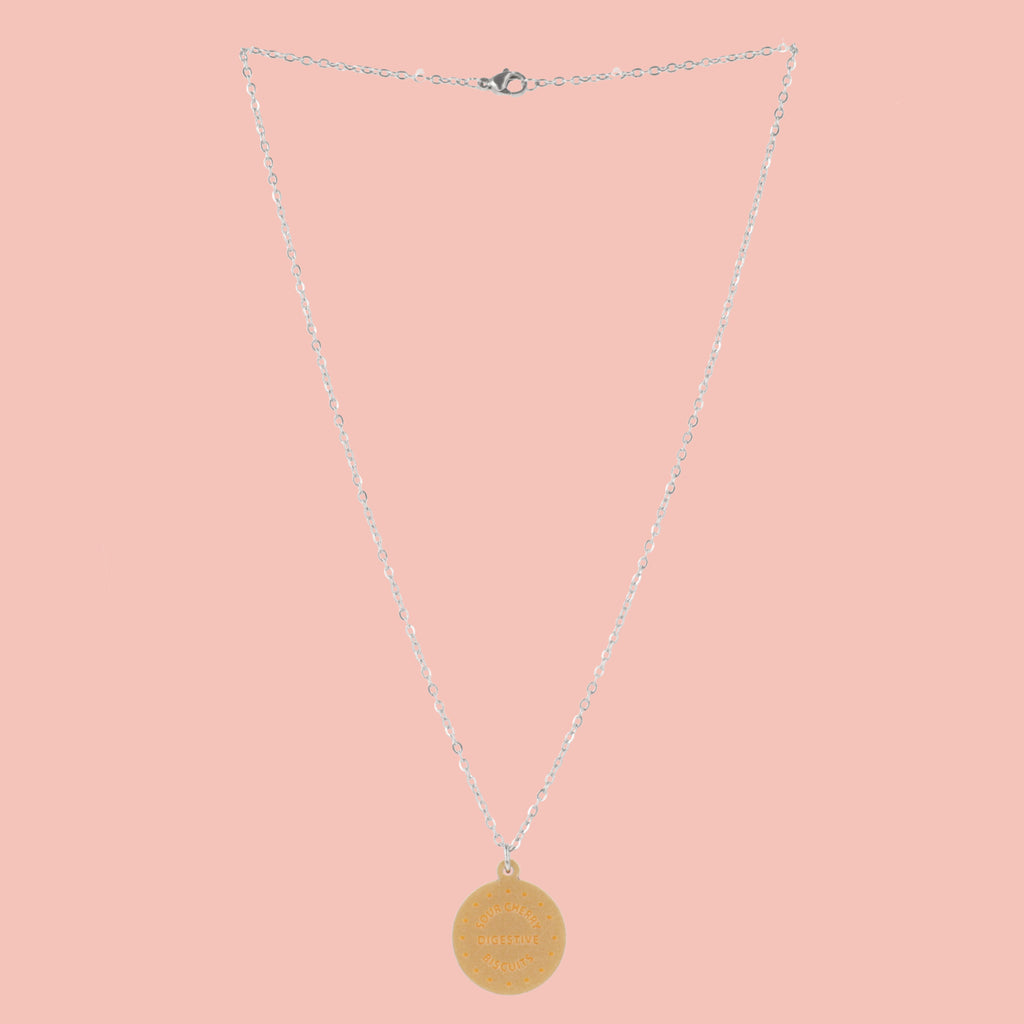 Necklace with a digestive biscuit pendant on a pink background
